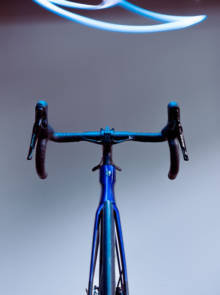 Blue road bicycle beneath a cyan light trail