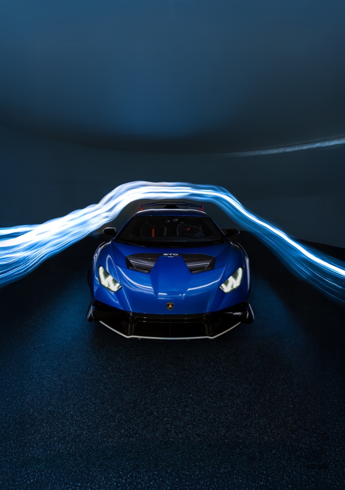 Blue sports car framed by white and blue light trails